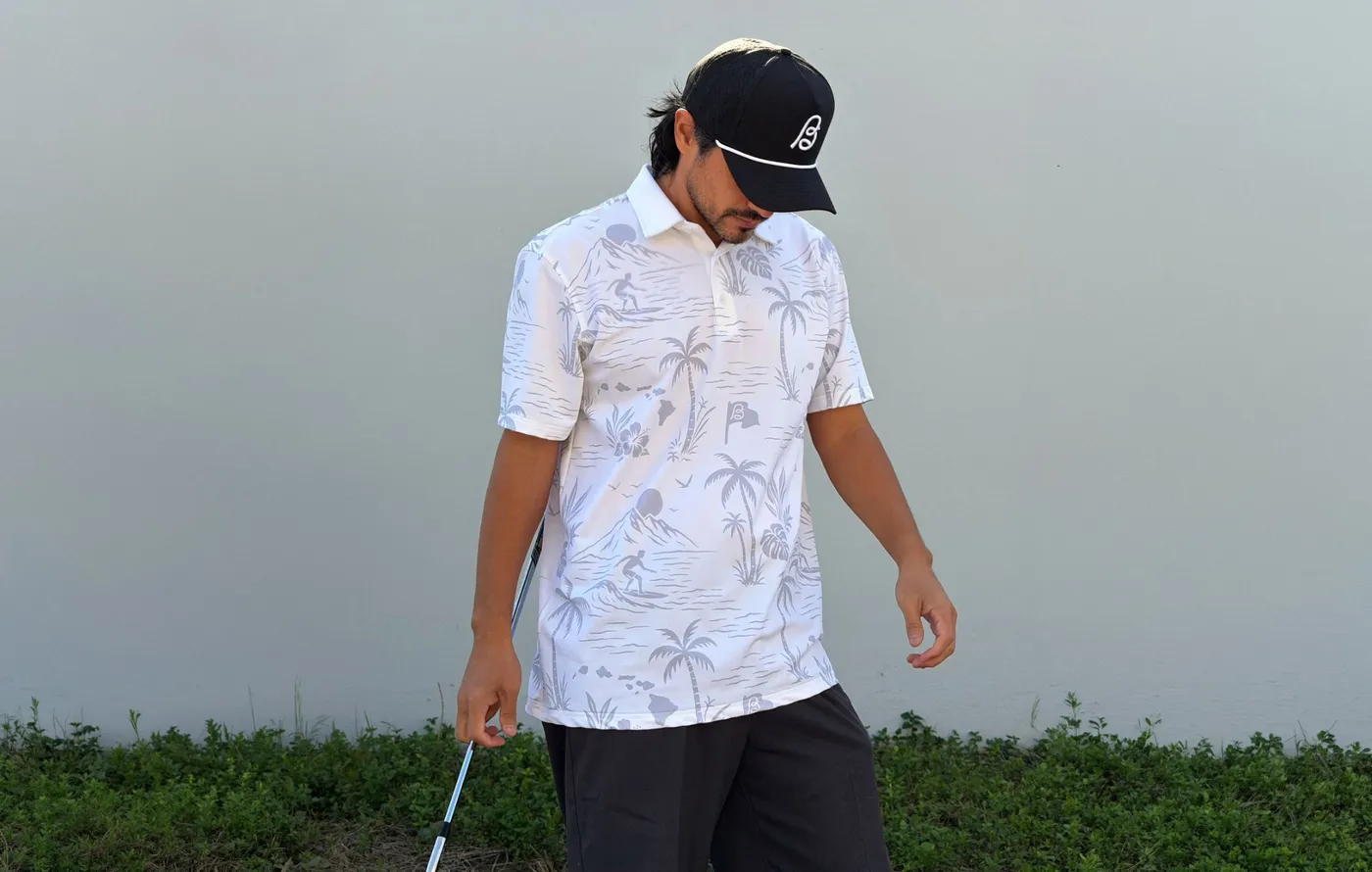 A golfer in a white Birdeaux polo with an all-over Hawaii pattern